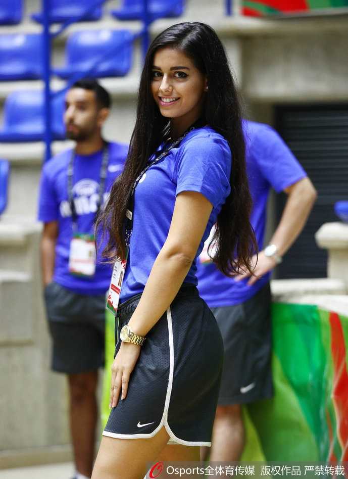 美女球迷举起手机自拍，脸上洋溢着灿烂的笑容，背景是满场的五星红旗