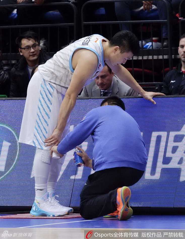 新疆队医和替补球员迅速冲进场内，关切地围绕在李根身边，李根紧锁眉头，低头查看自己的伤处，气氛紧张。