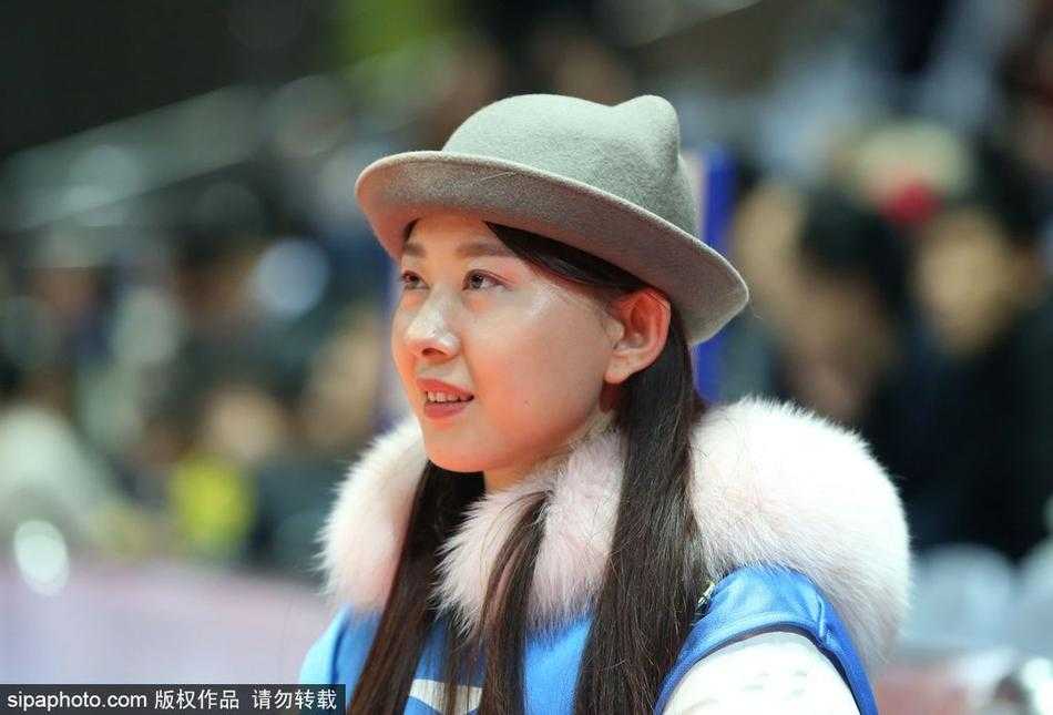 距离开赛还有一段时间，一位身着粉色外套的年轻女孩已独自坐在空荡的看台上，她眼神清澈，静静注视着场地中央正在热身的球员，仿佛在构思着稍后该如何为心爱的球队呐喊。