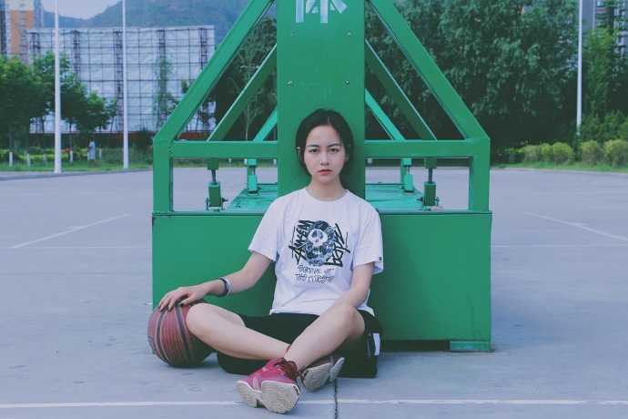 篮球女神孙夕雨:因詹姆斯而炽热,她的青春在球场上飞扬 孙夕雨身穿休闲运动背心,头戴棒球帽,手拿篮球站在球场边,眼神清澈明亮,展现出邻家女孩的运动活力。