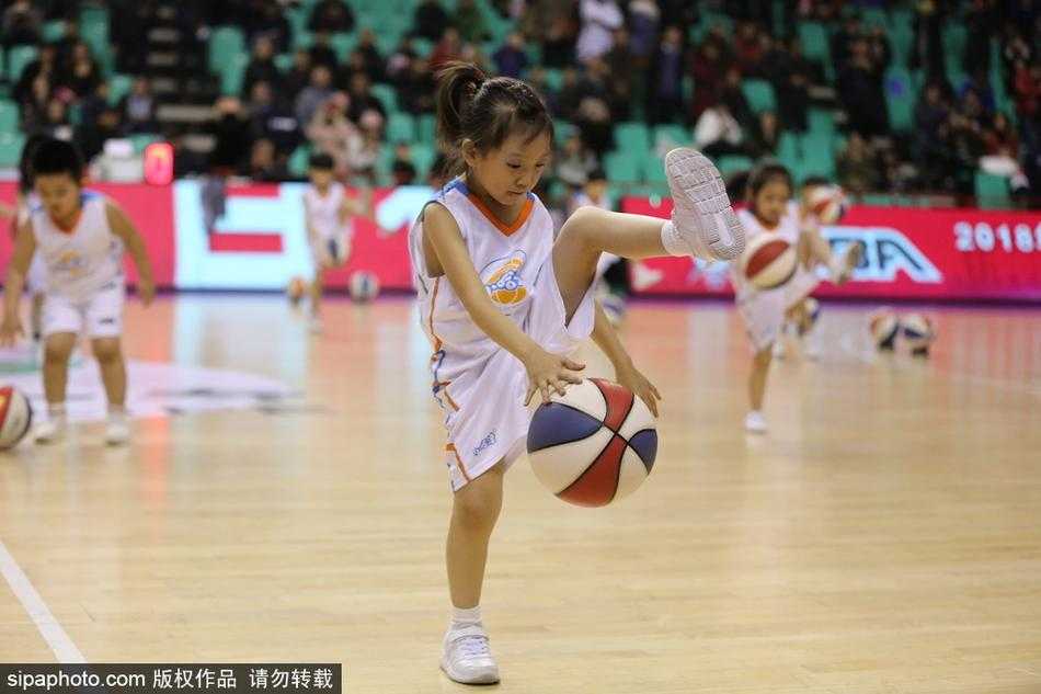 一群穿着红色篮球服的小朋友们在CBA赛场中央认真拍球，圆滚滚的篮球在他们小手中听话地上下跳动，眼神专注又可爱。