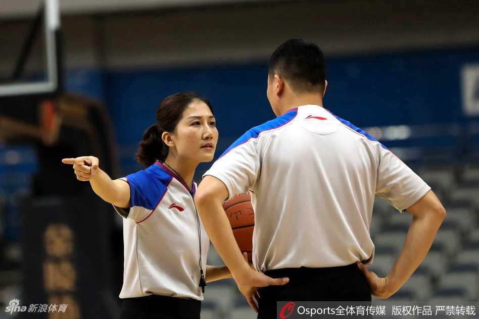 女裁判在人群中高高跃起，与争抢篮板的球员们一同腾空，她张开手臂维持着争球秩序
