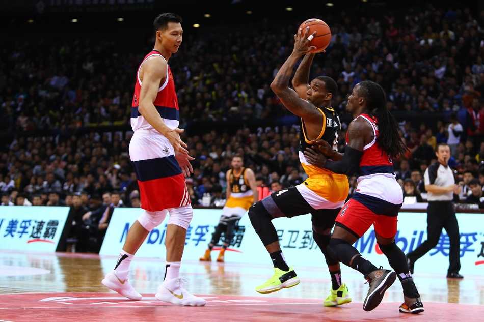 北区球员郭艾伦在人群中灵活穿梭，试图突破易建联的防守，这一瞬间充满了兄弟间较量的趣味与火花。