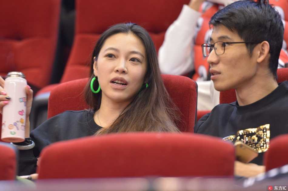 冬日暖阳洒在体育场的看台上，两位长发飘飘的女球迷裹着厚外套，正全神贯注地注视着赛场，她们的侧脸在逆光中显得格外立体而柔美。