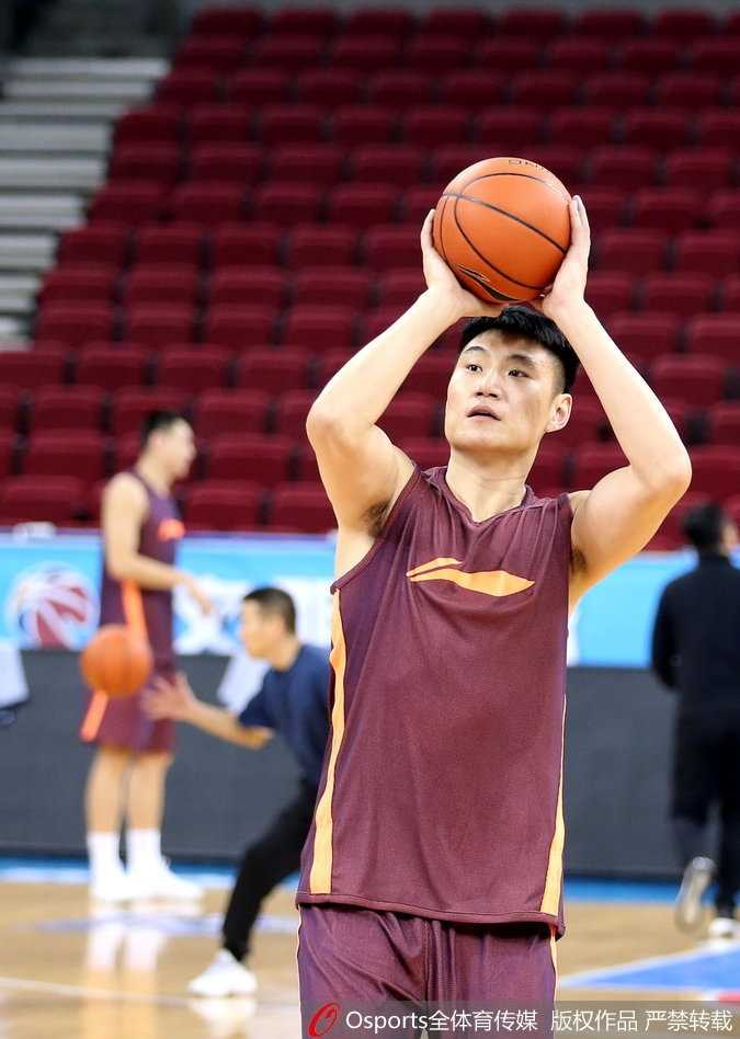 北京男篮的内线球员朱彦西在训练中跃起投篮，他的动作舒展，眼神瞄准篮筐，身后的场馆灯光映衬出他矫健的身姿。