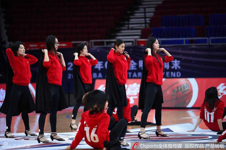 领队正在为队员纠正姿态，女孩伸展手臂线条流畅，形体训练一丝不苟。