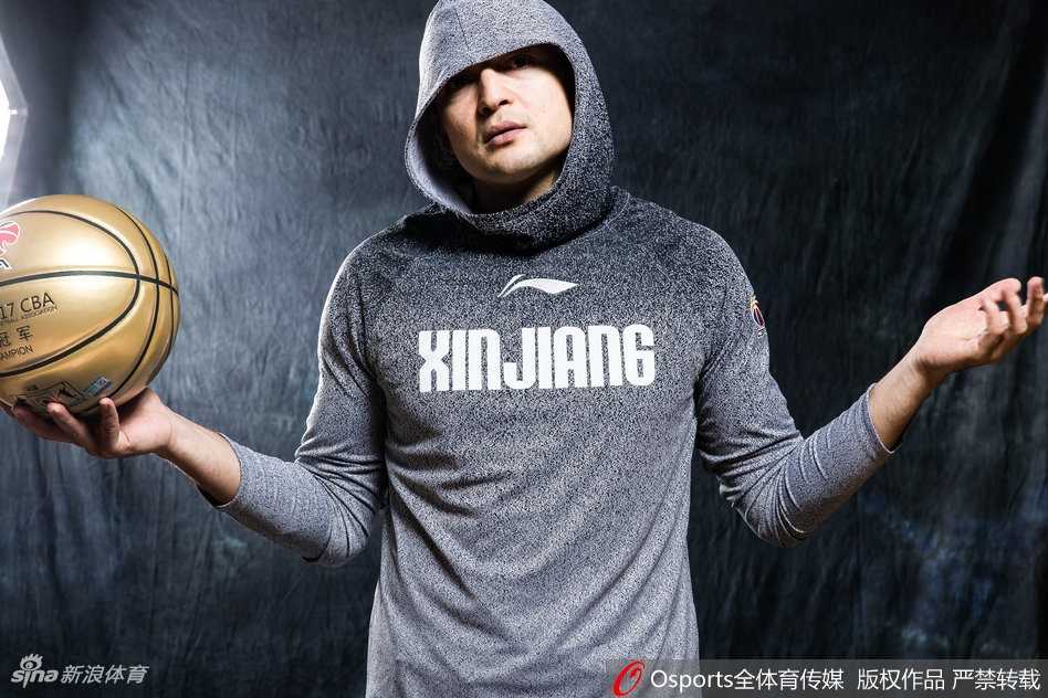 西热力江半身肖像，身穿浅色帽衫，头戴黑色毛线帽，身后是斑驳的墙壁，整体风格简约却极具嘻哈街头感