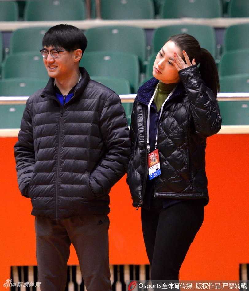 在训练结束后的场边，美女记者将话筒递向一位浑身湿透的新疆队主力球员，两人面带微笑进行着赛后简短的交流，背景是空旷的看台和整理器材的助理教练，氛围轻松而专业。