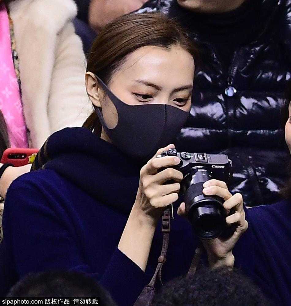 赛场边的深情守望:李晓旭爱妻变身摄影师 李旭身披大衣,手持专业相机,神情专注地站在场边,镜头紧紧追随着球场上的丈夫李晓旭