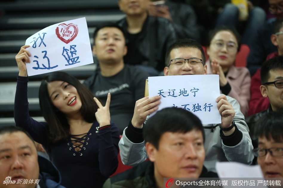 三位辽宁美女球迷在场边合影留念，笑容灿烂，她们身穿统一的辽篮助威服，青春洋溢，用笑容为球队加油打气。