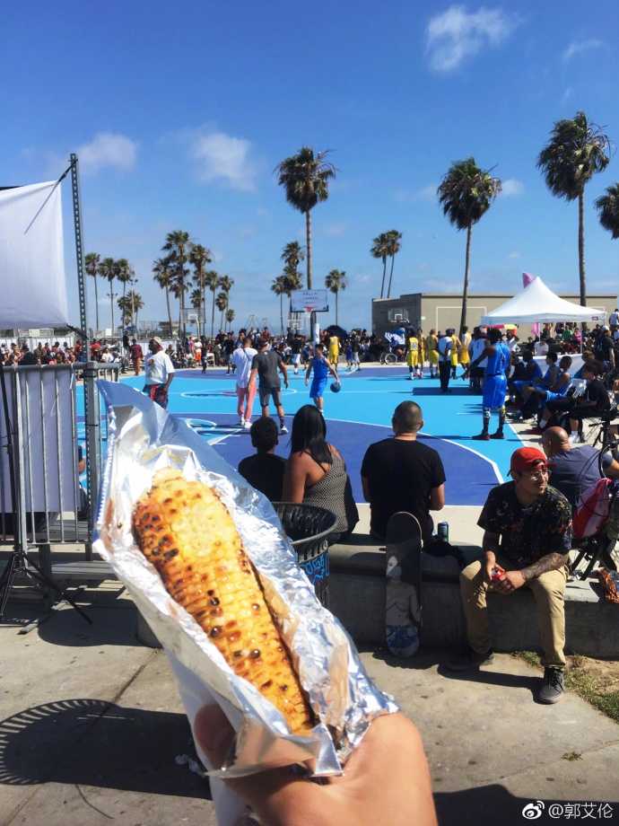 郭艾伦的美国特训日记:沙滩、烤苞米与篮球的快乐交响 黄昏的海滩边,郭艾伦与一群街头篮球手围在一起,他手里还攥着没吃完的烤苞米,完全融入了这片自由而热烈的篮球氛围中。