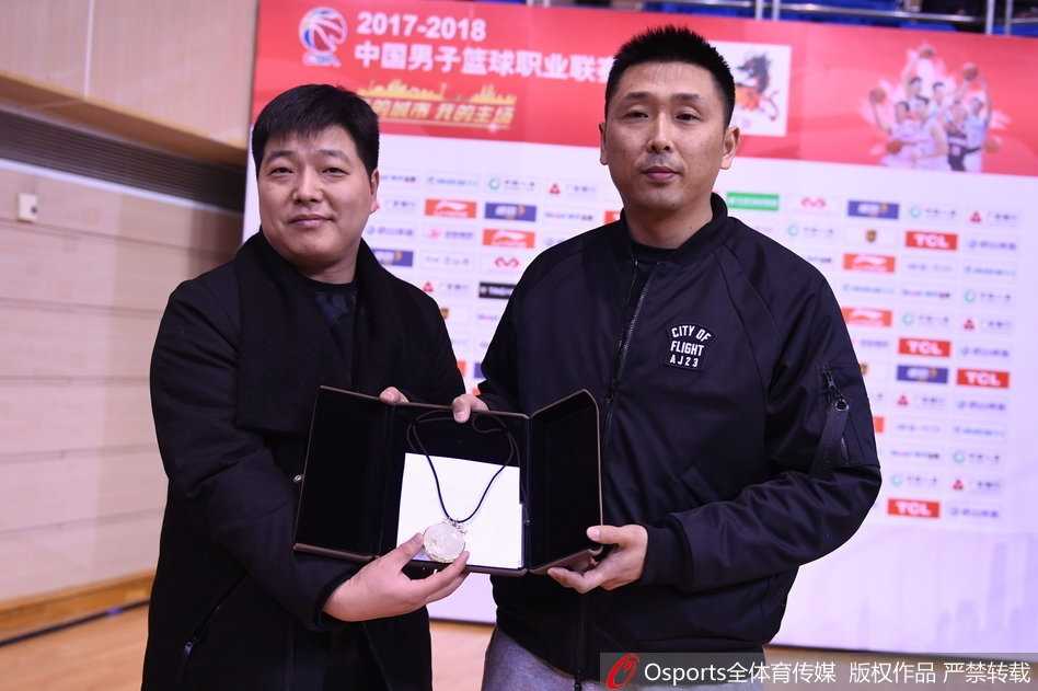 金镶玉寄深情:球迷匠心赠礼致敬胡雪峰传奇生涯 胡雪峰与球迷钱鑫在球场中央握手致意,两人之间传递的不仅是那块精美的金镶玉,更是江苏篮球二十余载的情感传承与球迷文化最真挚的体现。