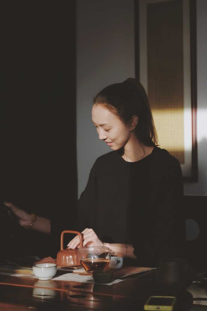 李晓旭爱妻置身于绿植环绕的阳台，手捧一本书籍，恬静优雅的气质与自然融为一体