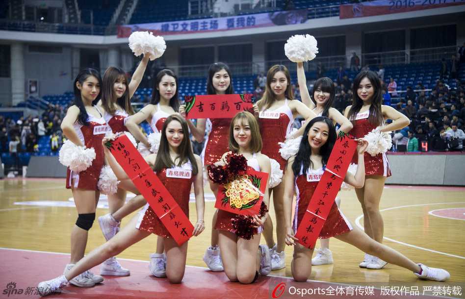 身着火红紧身衣的篮球宝贝扎着利落马尾，双手举起大红福字，眉眼弯弯笑得灿烂，身后虚化的篮球架映衬出她健康活力的身姿