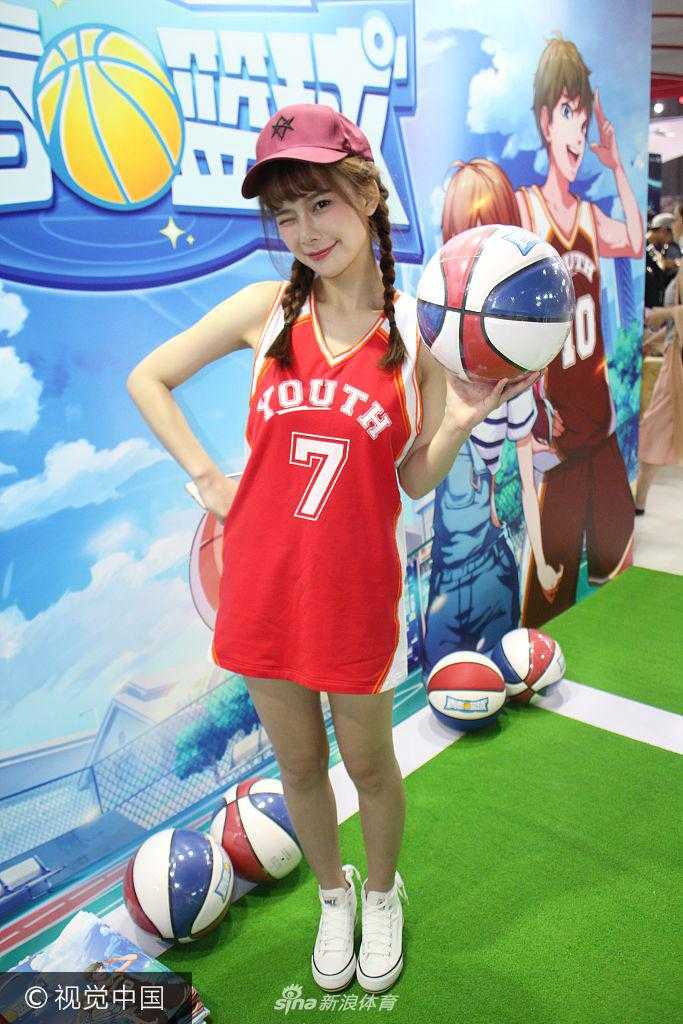 在展台的一角，两位篮球宝贝正在互相配合练习传球，她们神情专注而轻松，身体的律动与背后的游戏巨幅海报相映成趣，构成了一幅充满活力的画面。