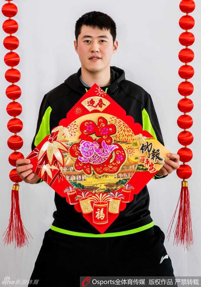 翟晓川独自持着卷轴年画，眼神专注而温柔，画中饱满的莲藕与锦鲤象征着年年有余，而他身后的篮球架则默默诉说着这是属于战士的新春守望。