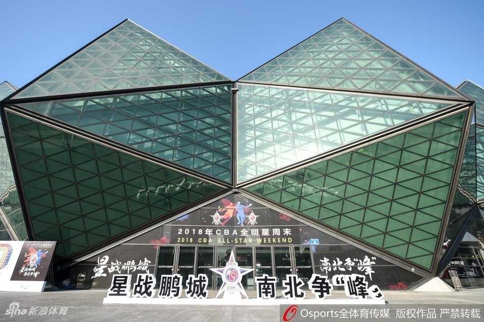 夕阳的余晖将大运中心染成温暖的橘红色，广场上人潮涌动，身穿各色球衣的球迷们手持门票，脸上洋溢着节日的喜悦，有序地通过安检进入球场。