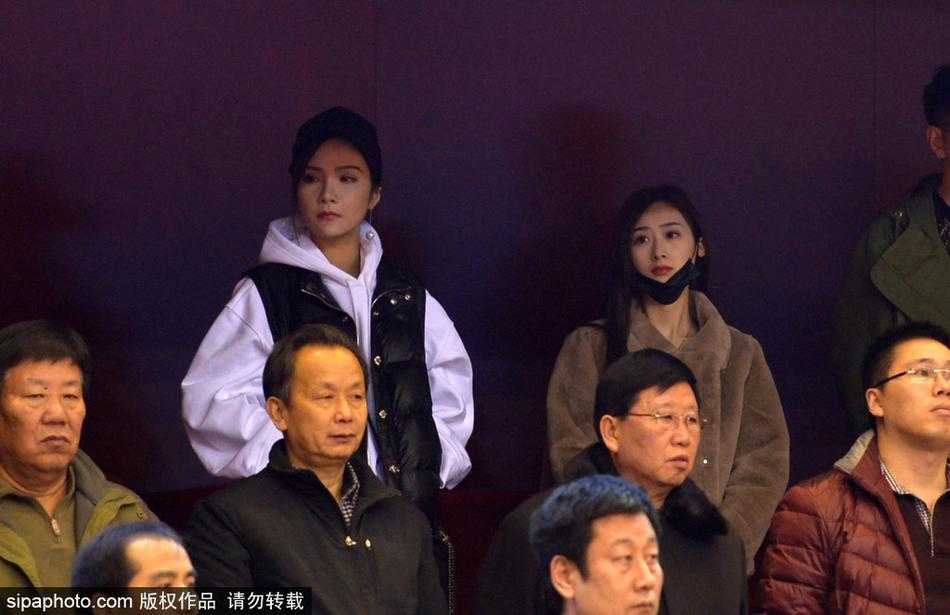 丁彦雨航女友身着一袭浅色衣衫，安静地坐在看台上，眼神中透露出对赛场上那个身影的默默关切。