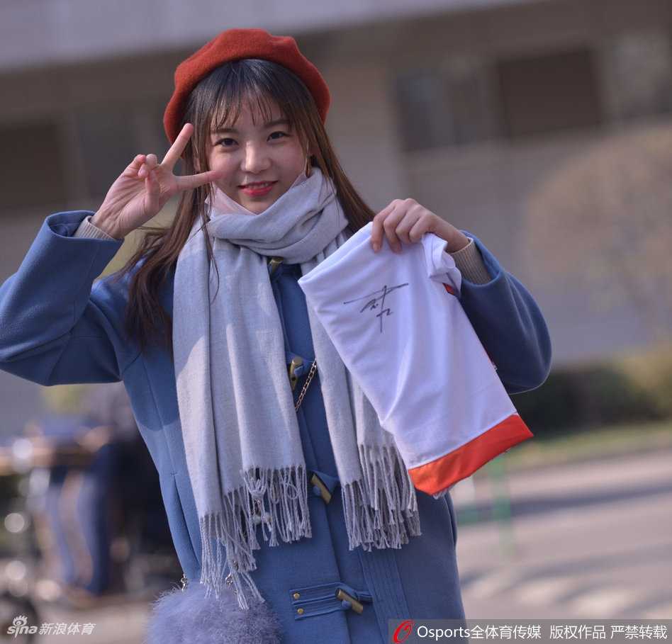 温柔一笑的女球迷，在喧嚣的赛场中显得格外宁静美好，她身着休闲外套，是时尚与体育的完美结合。